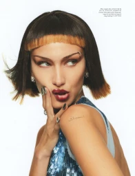 Close-up fashion portrait of Bella Hadid with a blunt bob haircut, dark glossy lipstick, and blue sequin top against a plain white background.