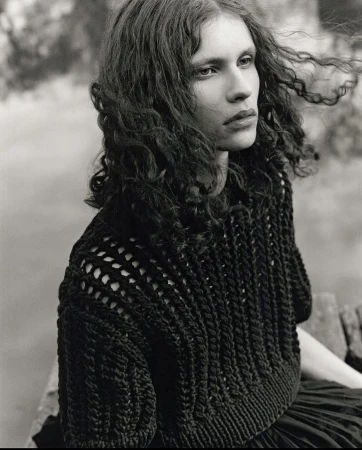 Monochrome portrait of a model with long curly hair wearing a textured dark knit sweater outdoors in Sydney.