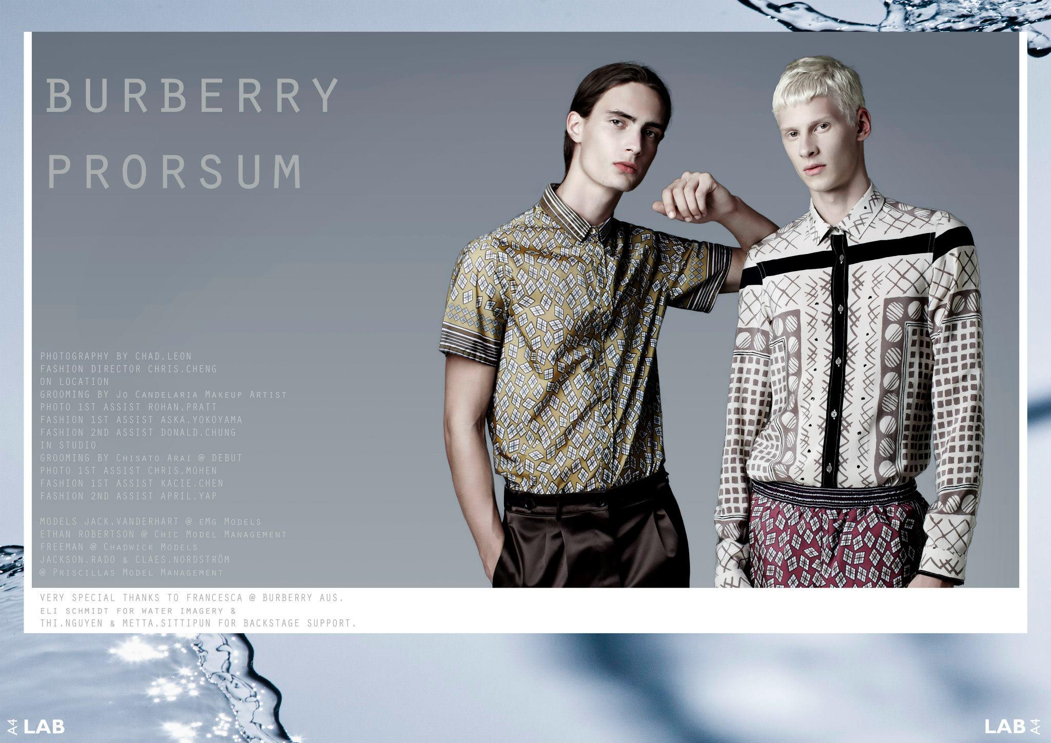 Fashion editorial shot featuring two adult male models wearing patterned shirts, one leaning against the other, with a cool grey backdrop.