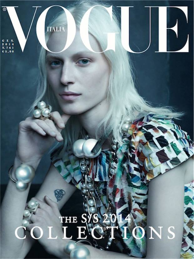 Vogue Italia cover featuring a model with blonde hair, wearing pearl jewellery and a patterned top against a grey background.