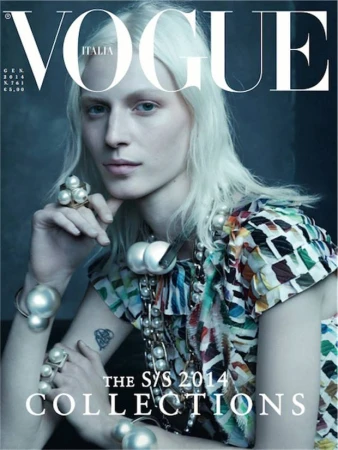 Vogue Italia cover featuring a model with blonde hair, wearing pearl jewellery and a patterned top against a grey background.