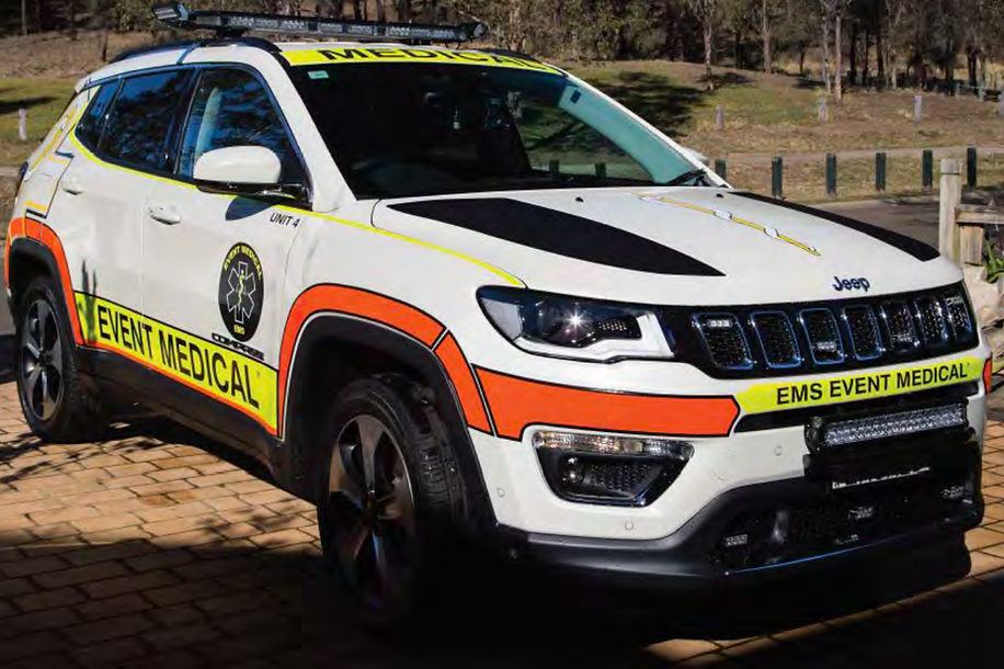 Jeep Compass EMS vehicle with medical markings, parked outdoors on a sunny day. The car is white with orange and yellow accents.