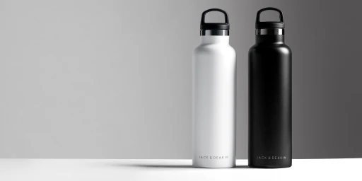 Two reusable water bottles, one white and one black, standing upright on a seamless white studio surface against a grey gradient background.