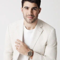 Close-up portrait of a man wearing a white blazer and a watch against a white background