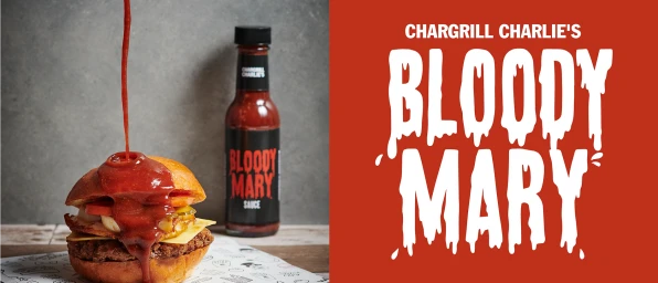 Burger with sauce being poured on top next to a bottle of Chargrill Charlie's Bloody Mary sauce against a red background.