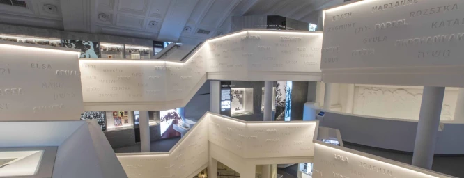 Modern architectural museum interior with multi-level white staircases and illuminated panels displaying names in Sydney by Marzipan Media