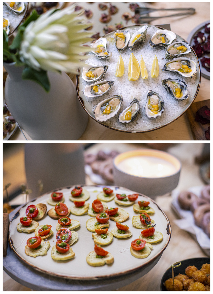 A spread of appetizers features plates of oysters with lemon wedges and crostini topped with tomatoes and herbs. The scene suggests fine dining.