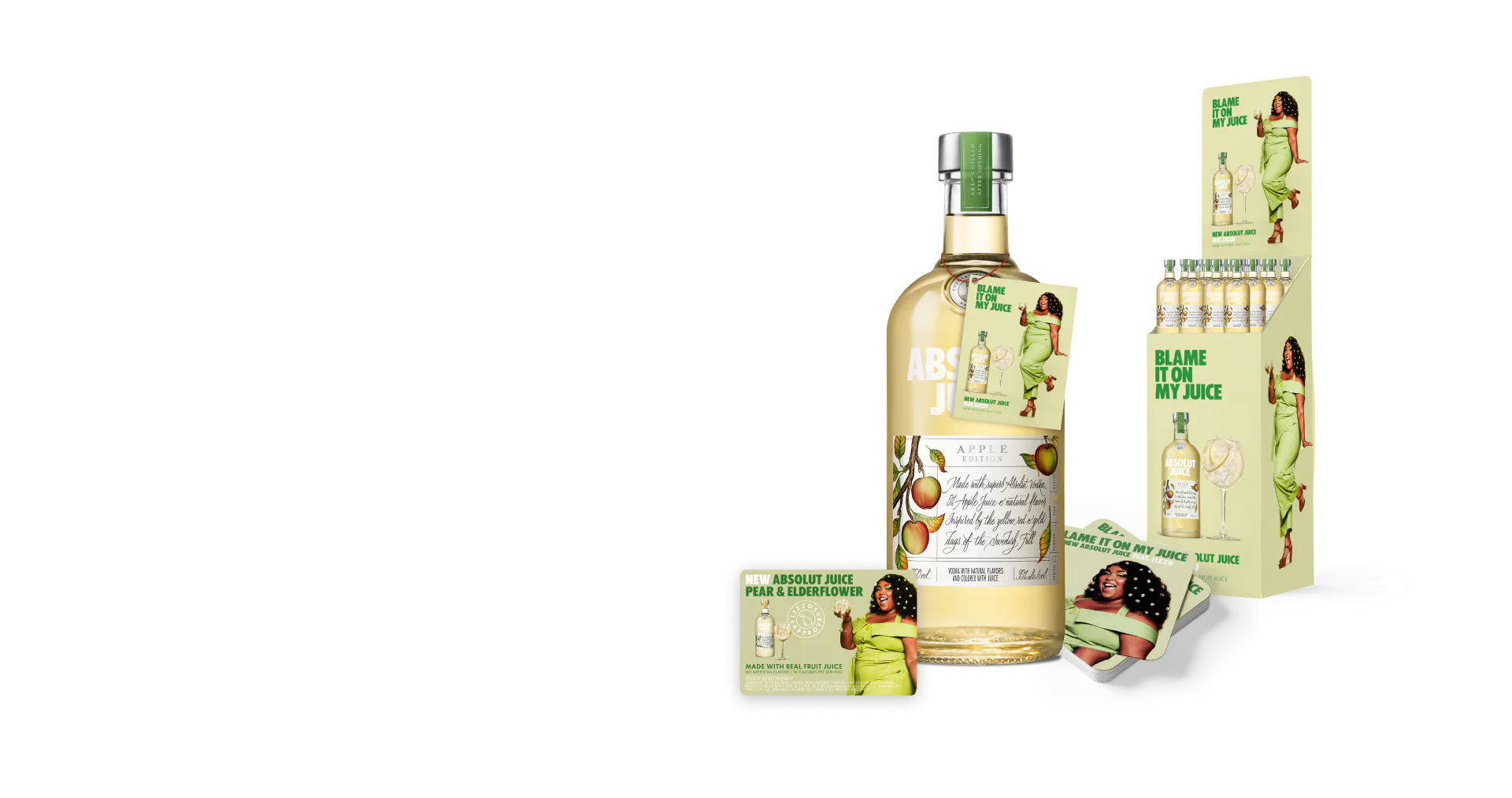 Absolut Juice Apple Edition bottle and marketing display featuring a woman in a green dress on a black studio background.