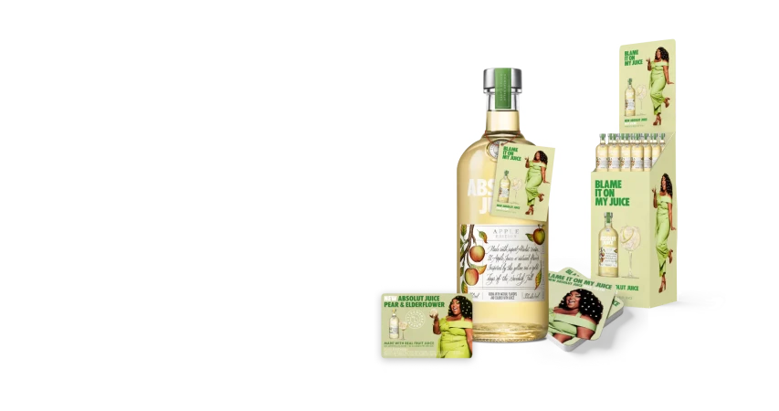 Absolut Juice Apple Edition bottle and marketing display featuring a woman in a green dress on a black studio background.