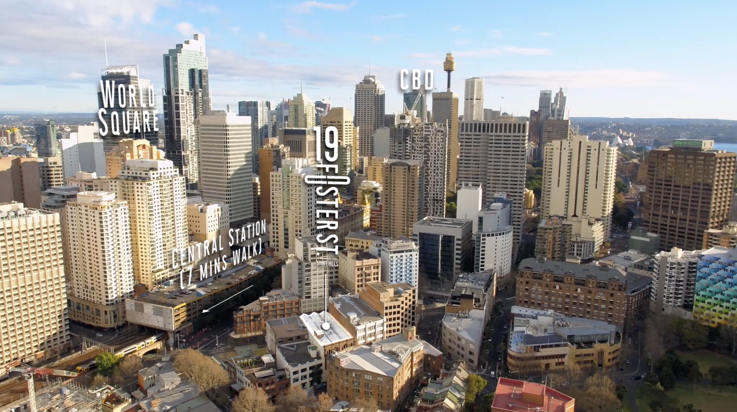 Aerial view of Sydney's cityscape featuring high-rise buildings, World Square, and the CBD under a bright sky, creating an urban panorama.
