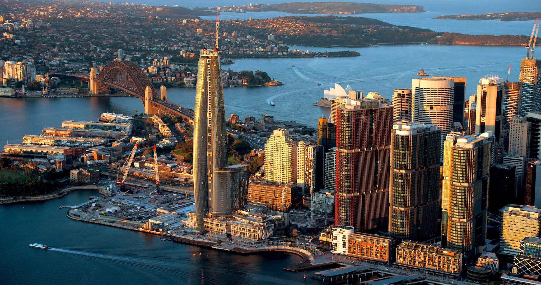 Sydney, Australia cityscape featuring modern architecture, the Harbour Bridge, and waterfront views at sunset.