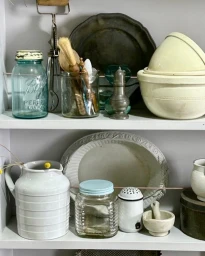 Vintage kitchen props including blue mason jar and ceramic mixing bowls on white shelves by Major and Tom