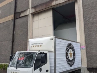 White removal truck parked in front of a brick warehouse loading bay in Sydney
