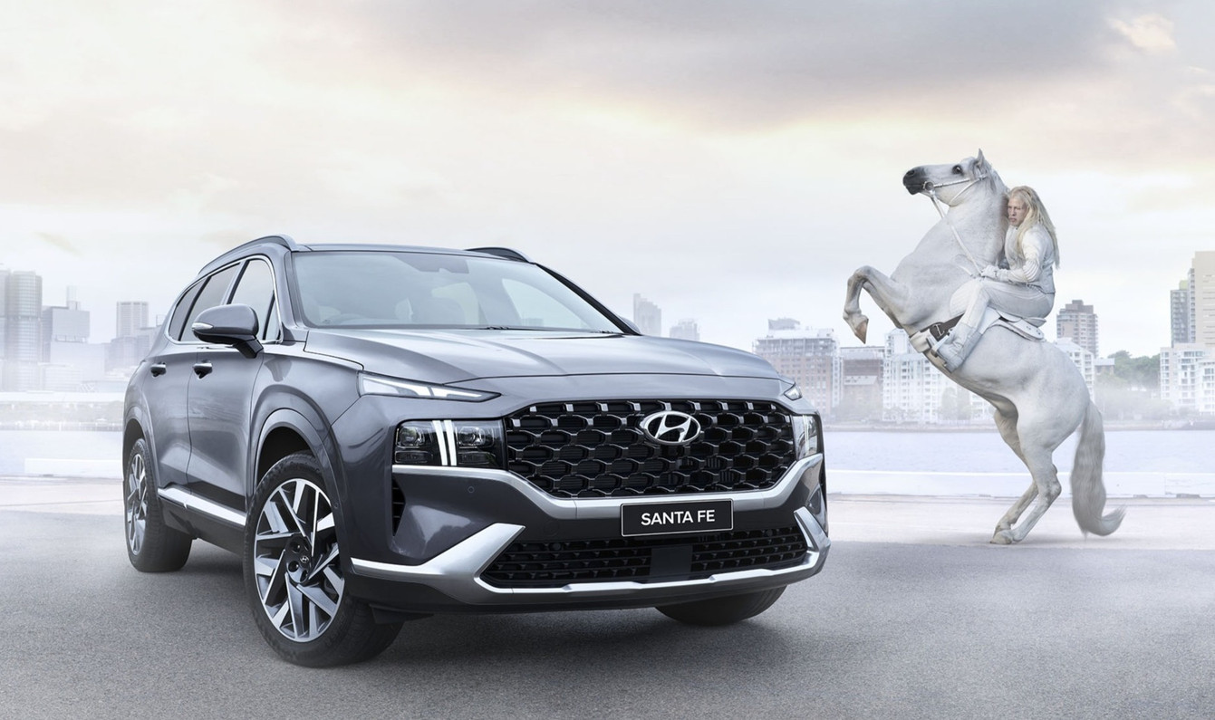Grey Hyundai Santa Fe SUV showcased in an automotive marketing shot featuring a white horse and rider in an urban environment.