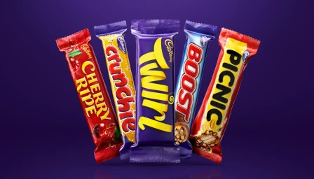 Five Cadbury chocolate bars including Cherry Ripe, Crunchie, Twirl, Boost, and Picnic arranged in a fan shape against a solid purple background.