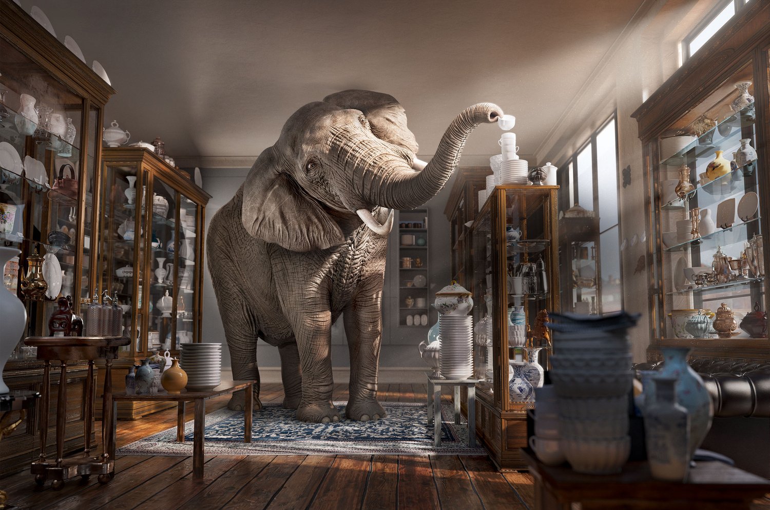 An elephant stands inside a china shop, using its trunk to place a teacup on a precariously tall stack of dishes.