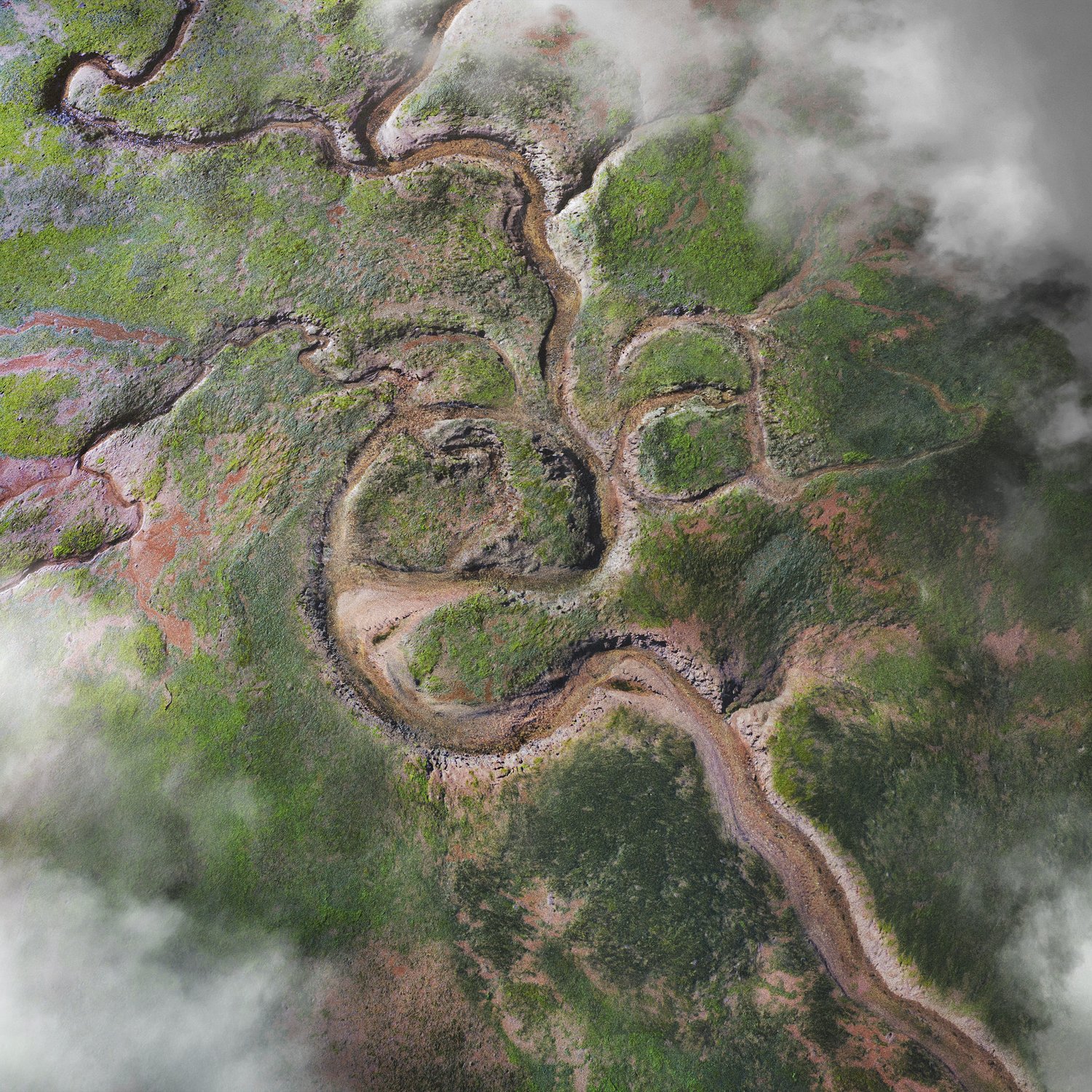Aerial view of river winding through a green and red landscape with low-lying clouds, showcasing natural beauty and water features.
