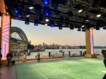 Outdoor stage build by Stage Kings in Sydney featuring a green turf floor and overhead rigging with theatrical lights overlooking the harbor