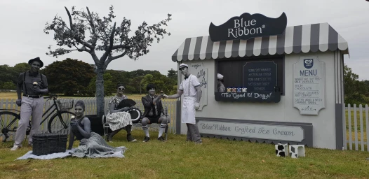 Live-action installation with monochromatic actors and a styled ice cream kiosk in a grassy park setting by Custom Elements