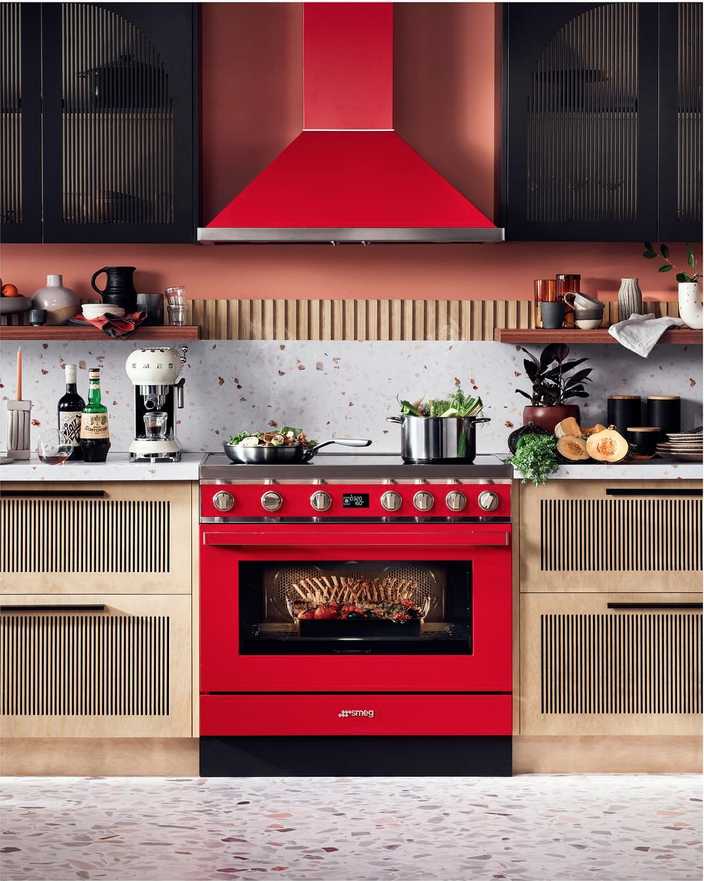 Red SMEG kitchen range cooker and hood, with matching cabinets and appliances in a domestic kitchen interior setting.