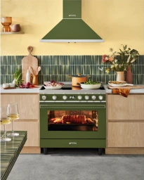 Green Smeg range cooker and matching extractor hood in a styled kitchen interior with wooden cabinets