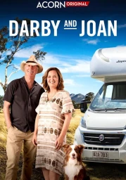 A smiling older man in a straw hat and an older woman standing outdoors next to a white motorhome with a dog sitting in front.