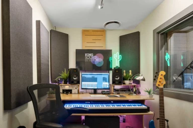 Audio recording studio control room in Sydney featuring a wooden desk, studio monitors, MIDI keyboard, and acoustic wall panels.
