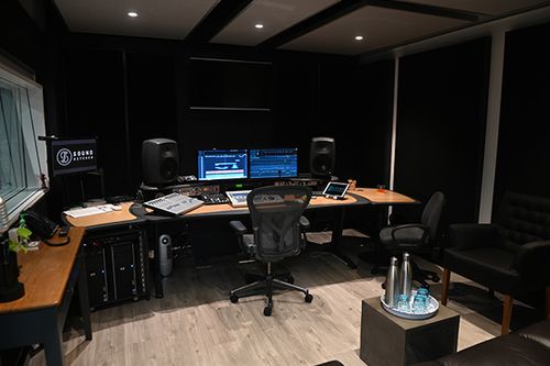 Acoustic panels and audio mixing setup in a dimly lit professional music recording studio with computer monitors and equipment.