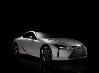 Silver luxury sports car parked against a pure black background with low key studio lighting