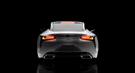 Rear view of a silver luxury sports car with illuminated red taillights against a pure black background