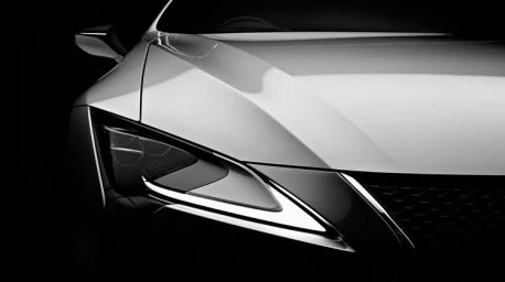 Monochrome close-up of a modern luxury car front headlight and sculpted hood lines against a dark background by d1 Studios.