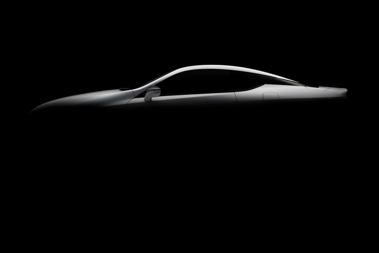 Sleek, silver car with a smooth silhouette highlighted against a dark background in an automotive studio setting. Automotive design.