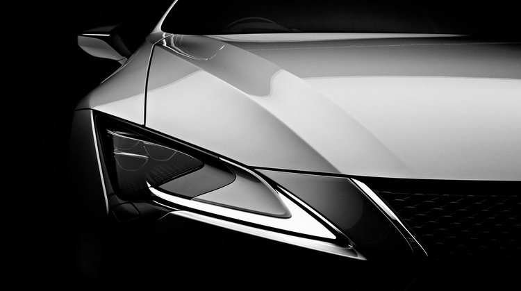 Close-up shot of a black and white Lexus car showcasing its sleek design, headlight details, and glossy finish in a dark studio setting.