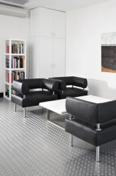 Modern photo studio interior featuring black leather armchairs, a white coffee table, and metal treadplate flooring.
