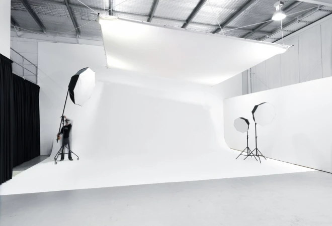 Professional photo studio in Melbourne with white cyclorama wall, large overhead diffuser, and studio lights.