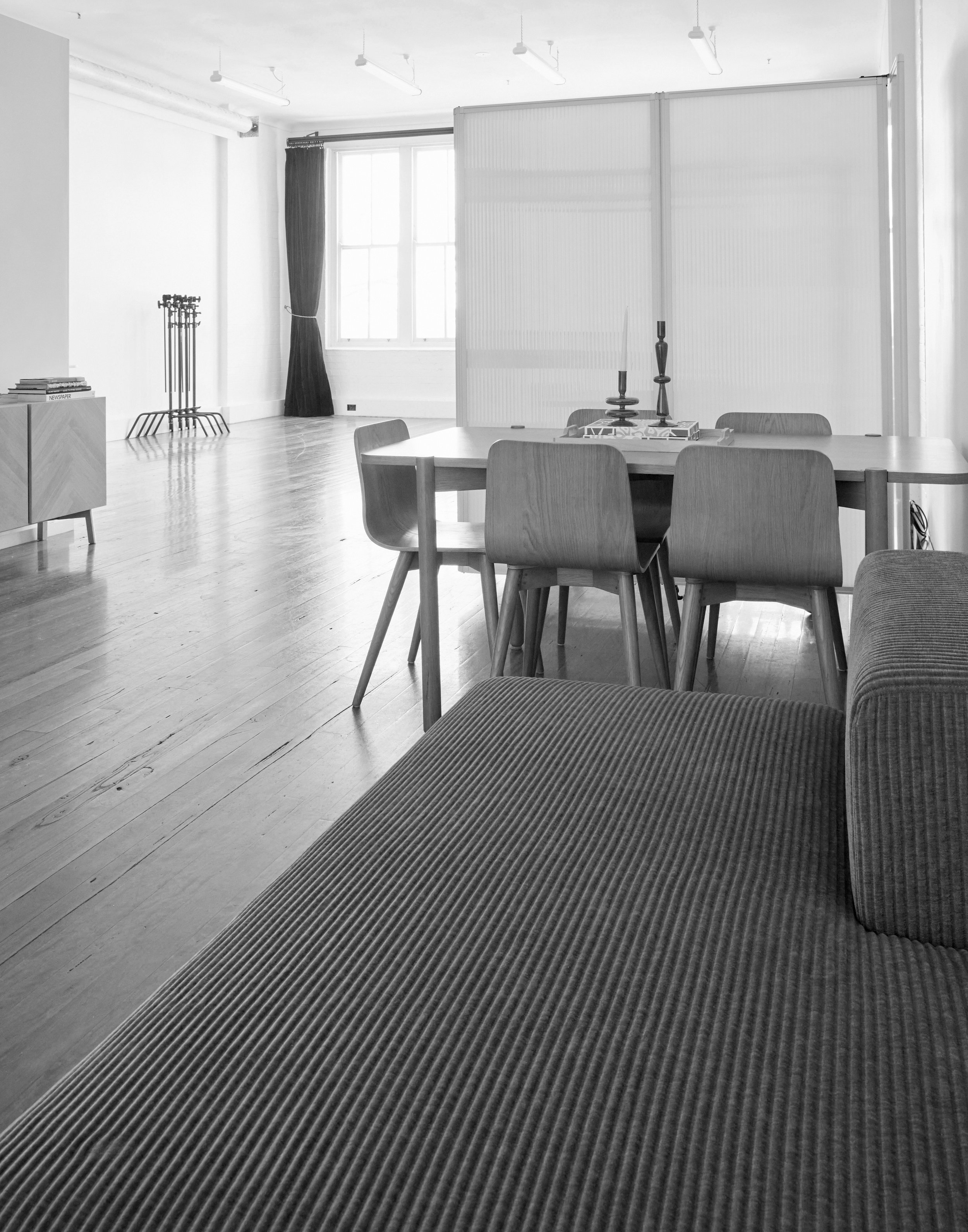Contemporary interior with a gray ribbed sofa, wooden table and chairs, set against a bright window and neutral color palette.