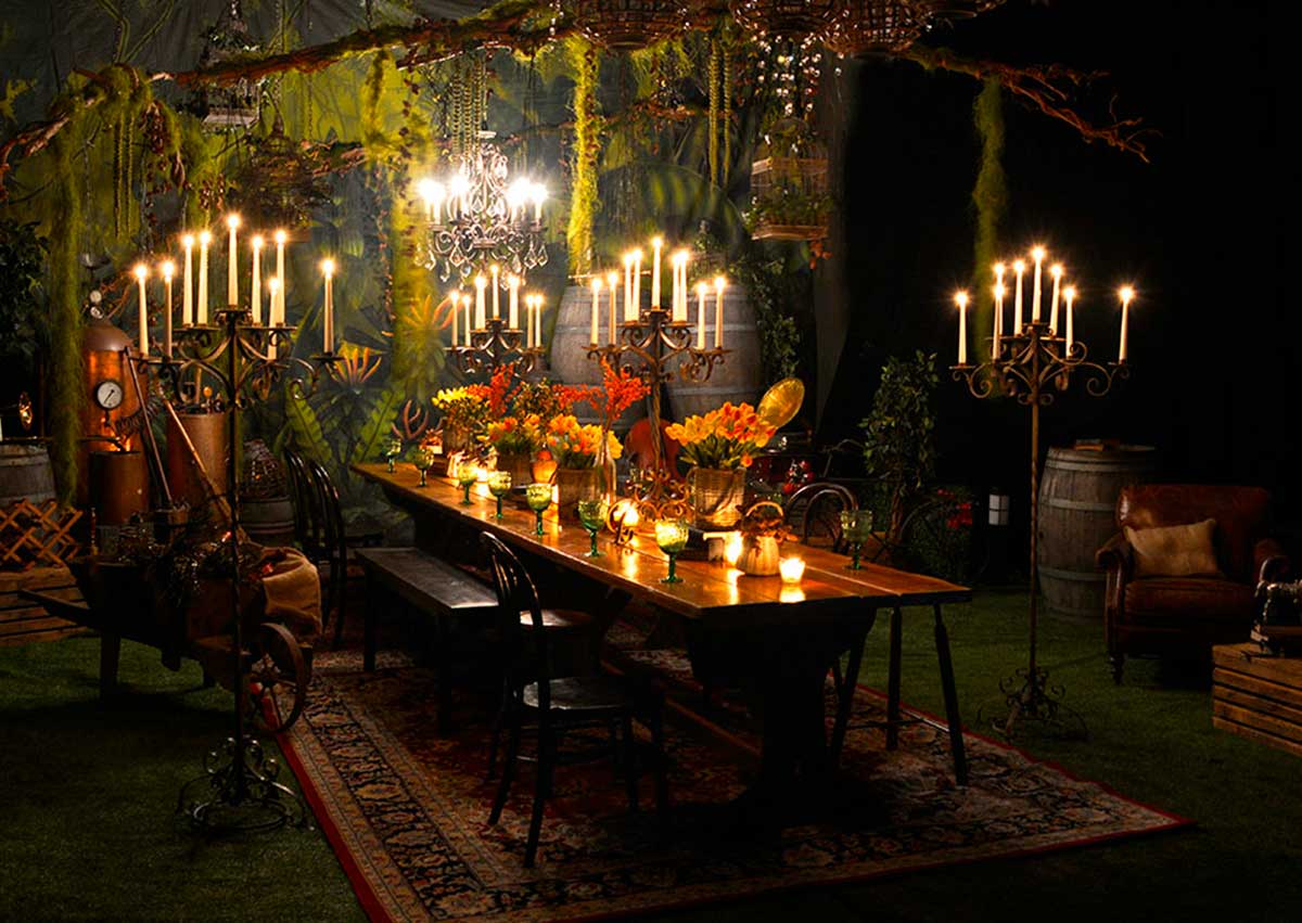 Candlelit formal dining table with floral centerpiece and surrounding decor elements, evoking a romantic ambiance in a natural setting.