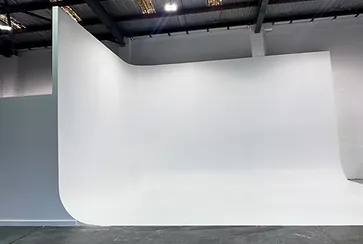 Minimalist shot of a white seamless backdrop in a photography studio with concrete floor, emphasizing simplicity and professional studio setup.