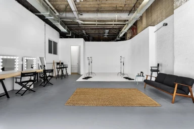Spacious industrial photo studio in Sydney with white cyclorama wall, makeup vanities, and concrete floors.