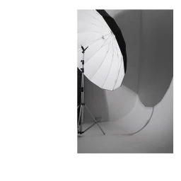 Studio photo equipment featuring a large white umbrella reflector on a metal light stand against a white sweep background.