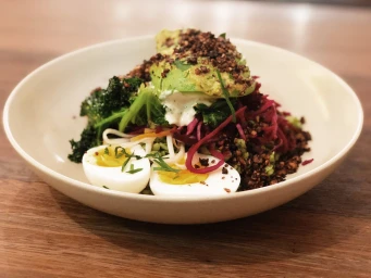 A gourmet salad bowl with sliced avocado, boiled eggs, shredded beetroot, and greens on a wooden surface by Four Ate Five Sydney