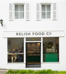 Exterior facade of Relish Food Co in Sydney showing white building, storefront signage, and customers inside.