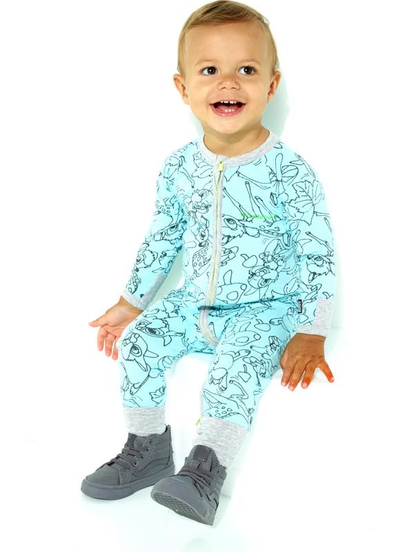 Cute baby wearing patterned aqua pajamas and grey high-top shoes sitting against a white backdrop in a studio setting.