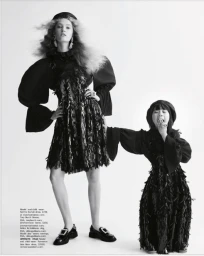 Monochrome fashion editorial image featuring a tall model and a child model in black dresses standing against a white seamless backdrop.