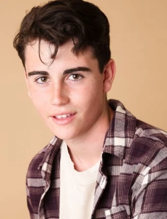 Headshot of a young adult male with brown hair wearing a plaid shirt against a neutral background in a studio setting. 