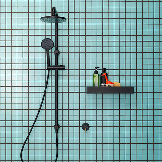 Modern black shower fixture on light blue tile wall with a small shelf holding bottles and a sponge in a minimalist bathroom.