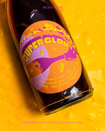 Artistic product shot of a wine bottle with a colorful label on a bright yellow textured background. Modern product photography.