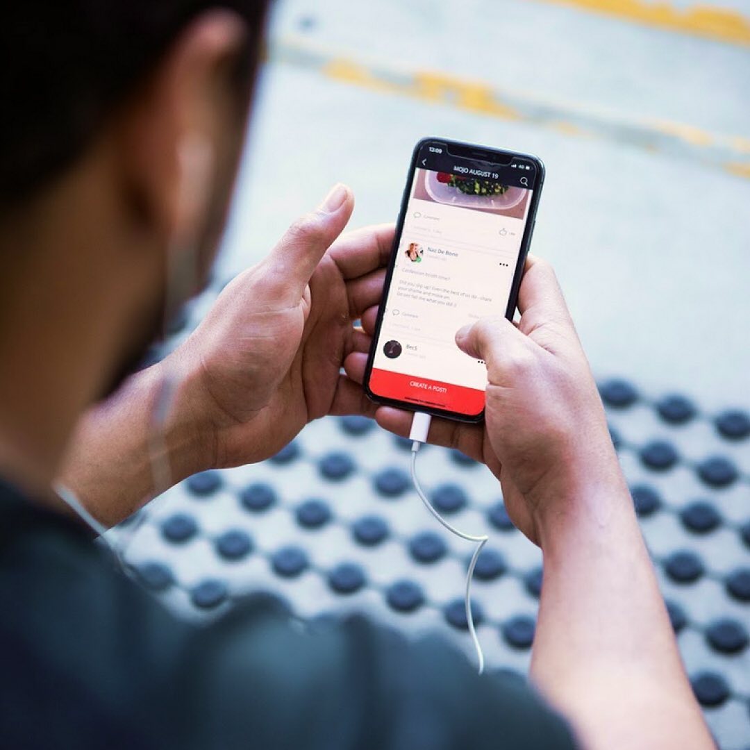 Person using a smartphone with a food-related app interface while holding it with two hands, showcasing mobile technology in everyday use.