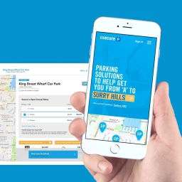 Hand holding a white smartphone displaying a parking application interface against a blue background.