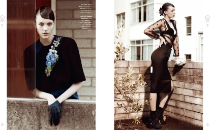 Two-page magazine spread showing a model in black attire with blue floral embellishments and dark gloves against a brick building exterior.